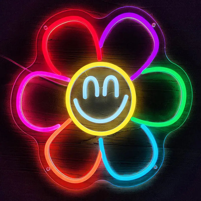 Smiley Flower Neon LED Sign head-on against a wooden wall, petals in red, purple, green, blue, orange and pink