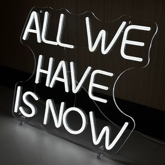 All We Have Is Now Neon LED Schild schräg von der Seite, Standfüße und klare Acrylkante gut sichtbar