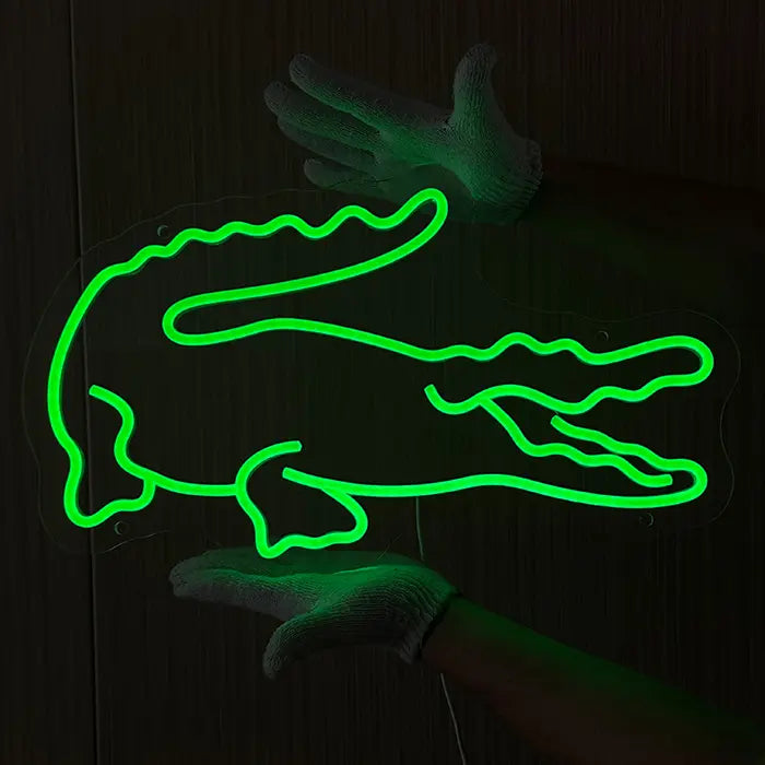 Krokodil Neon LED Schild leuchtet grün, freihändig vor einer dunklen Holzwand zur Platzierung gehalten