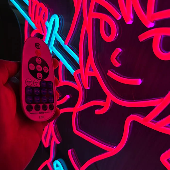 Sekira V Miaukuza Neon LED Schild mit Dimmer-Fernbedienung im Vordergrund, das Motiv leuchtet dahinter