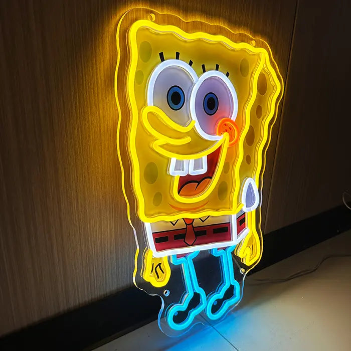 Schwammfigur Neon LED Schild schräg von vorn, warmes gelbes Licht strahlt auf die Holzwand dahinter