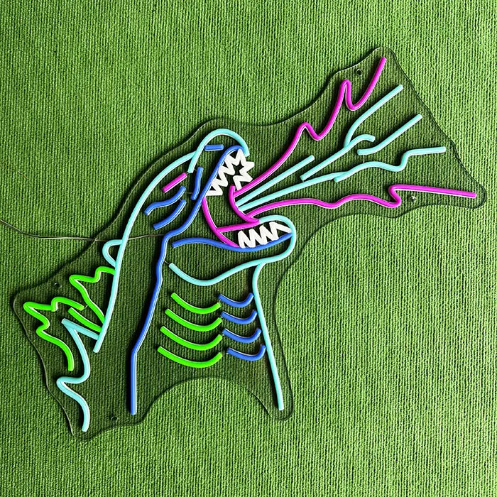 Godzilla Neon LED Sign switched off on a green surface, the complete contour visible