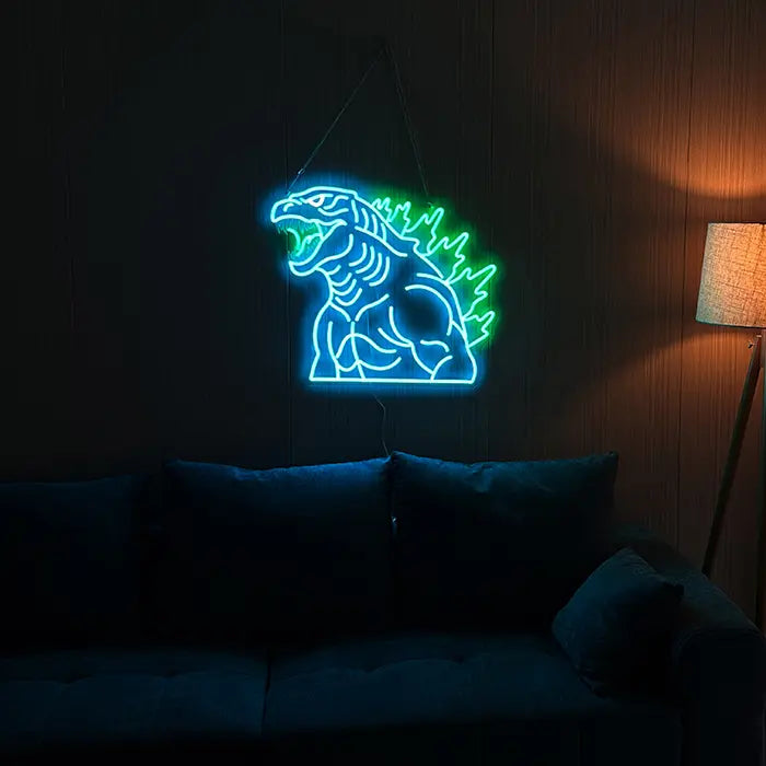 Godzilla Neon LED Sign on a dark wall above a sofa, a warm floor lamp beside it