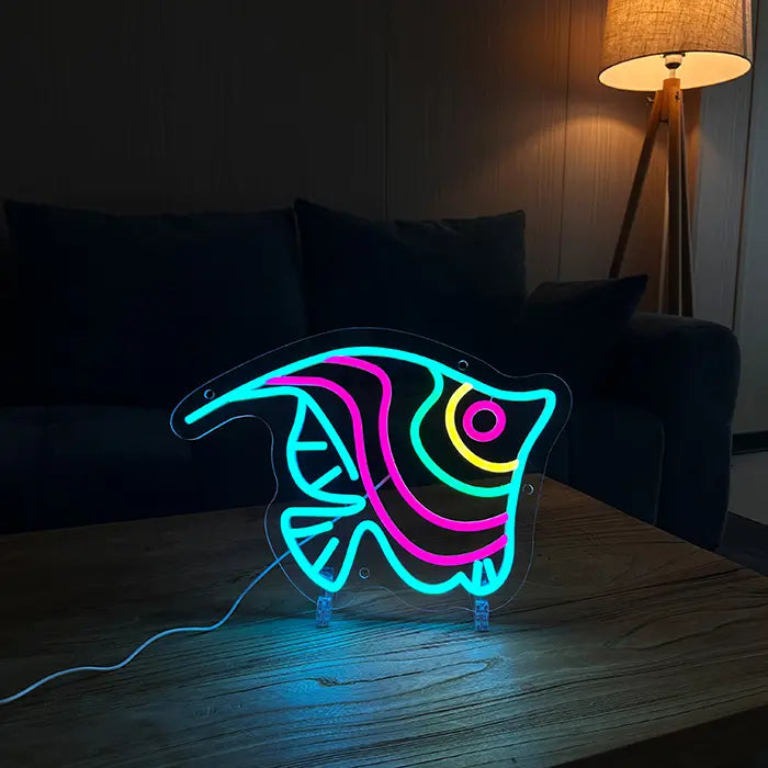 Ocean Fish Neon LED Sign on the coffee table in a darkened living room with a sofa and floor lamp behind