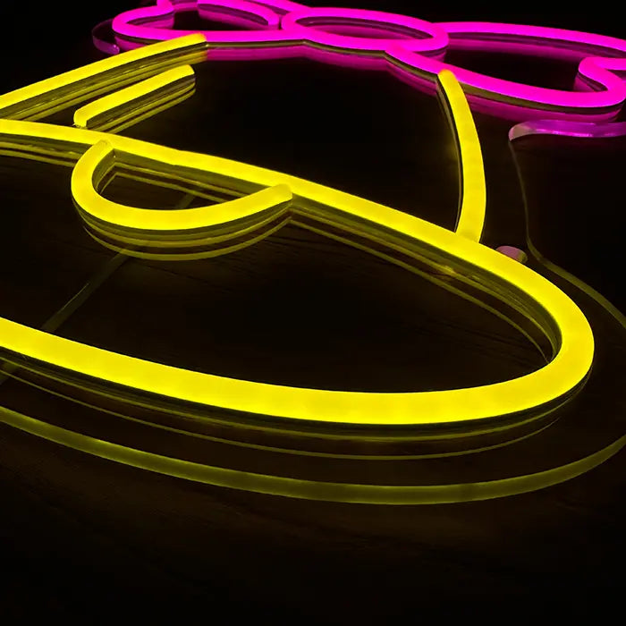 Little Bell Neon LED Sign in close-up, yellow and pink neon tubing on the clear acrylic panel
