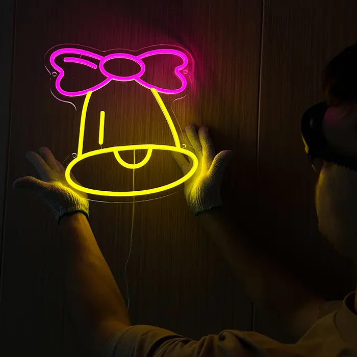Little Bell Neon LED Sign held against the wall while being aligned, the cable running down and away