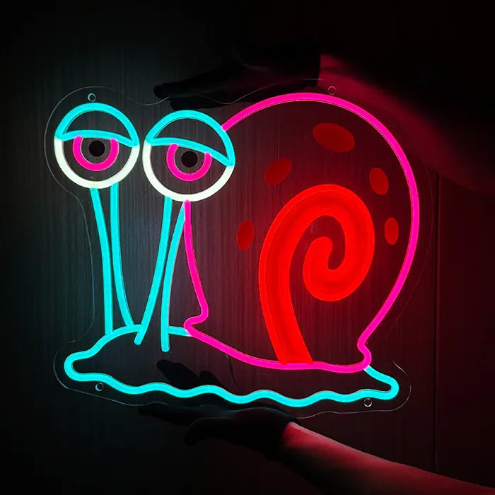 Gary the Snail Neon LED Sign held from below with both hands, the motif glowing strongly