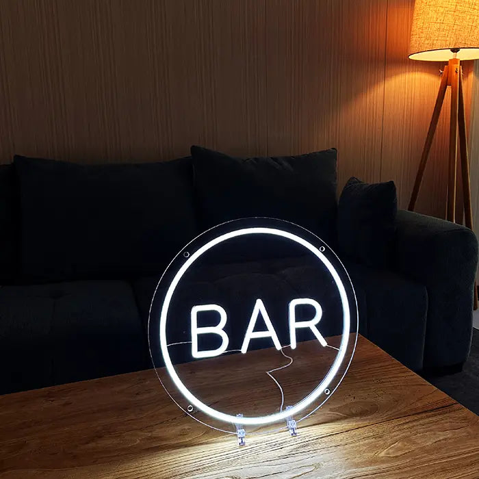 BAR Neon LED Sign on the coffee table in a darkened living room with a sofa and floor lamp behind