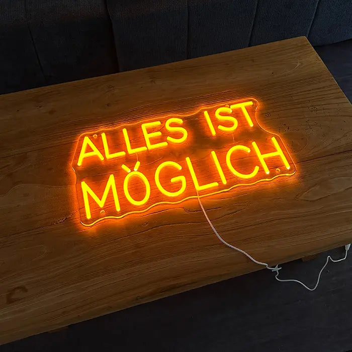 Anything Is Possible Neon LED Sign lying on a wooden table, lettering glowing orange