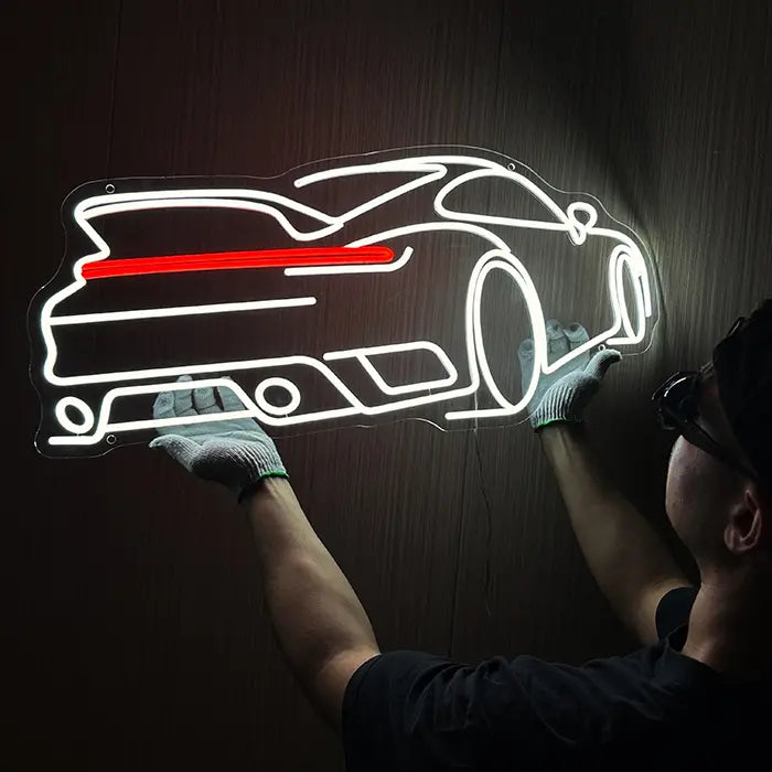 GT Sports Car Neon LED Sign being lined up on the wall, a person in gloves holds it in place