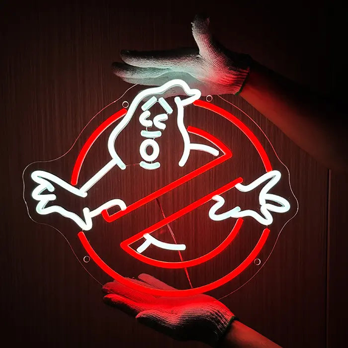 Ghostbusters Logo Neon LED Sign being held against a dark wall with gloves