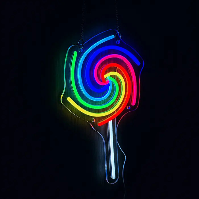 Lollipop Neon LED Sign hung on chains in front of a dark wall, spiral glowing in rainbow colours