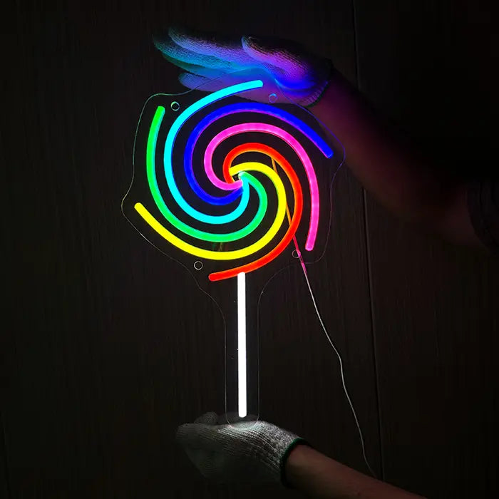 Lollipop Neon LED Sign being held against a dark wooden wall with gloves and lined up