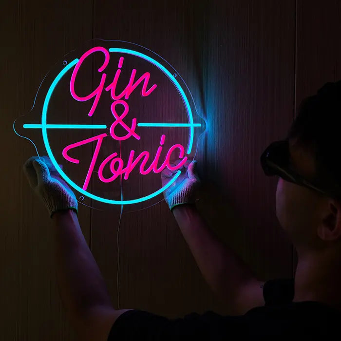 Gin & Tonic Neon LED Sign being lined up on the wall, a person in gloves holds it at the side