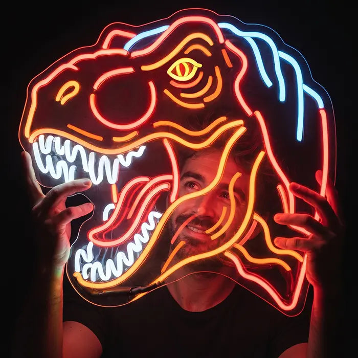 T-Rex Dino Neon LED Schild wird von einem Mann vor dem Gesicht gehalten und zeigt die XXL-Größe von 70 cm