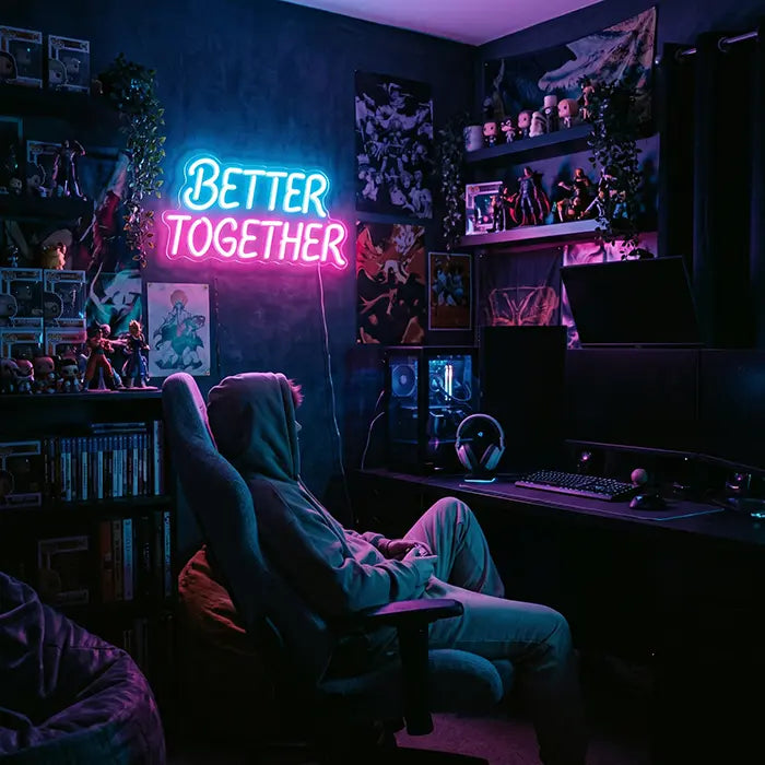 Better Together Neon LED Sign in blue-pink in a gaming room with figure shelves, a person in a gaming chair in front