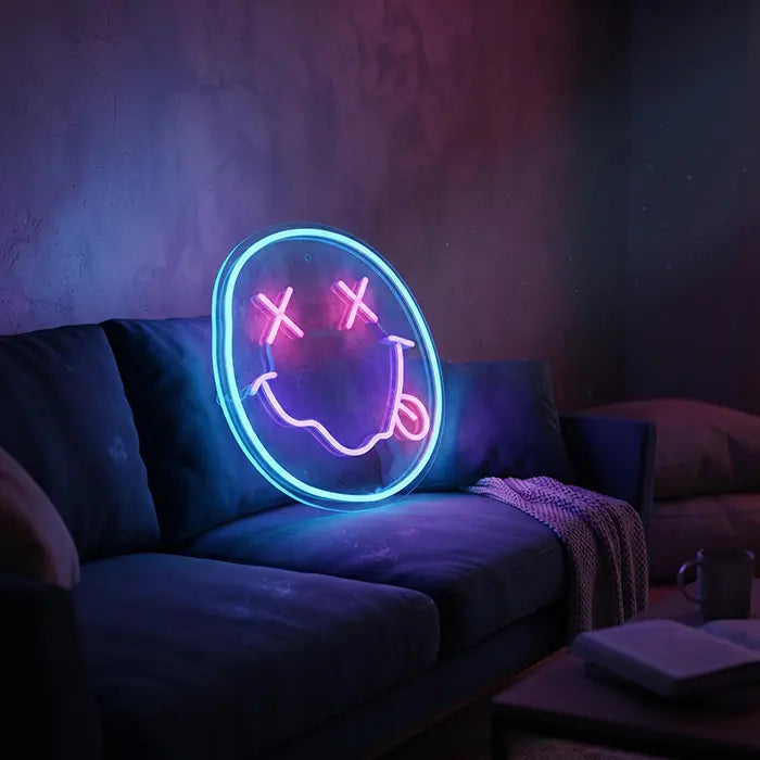 Smiley Neon LED Schild aufgestellt auf einem dunkelblauen Sofa im abgedunkelten Wohnzimmer