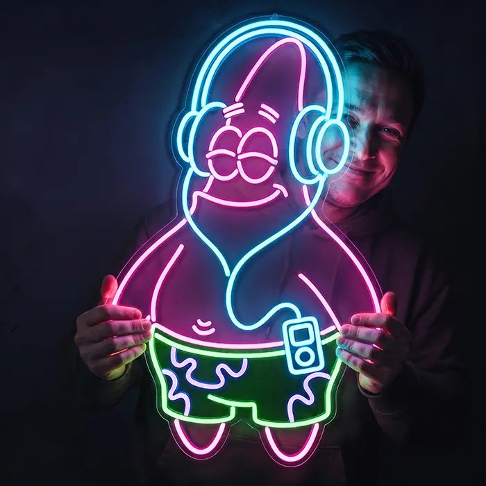 Patrick Kopfhörer Neon LED Schild wird von einem Mann in den Händen gehalten und leuchtet ihm ins Gesicht