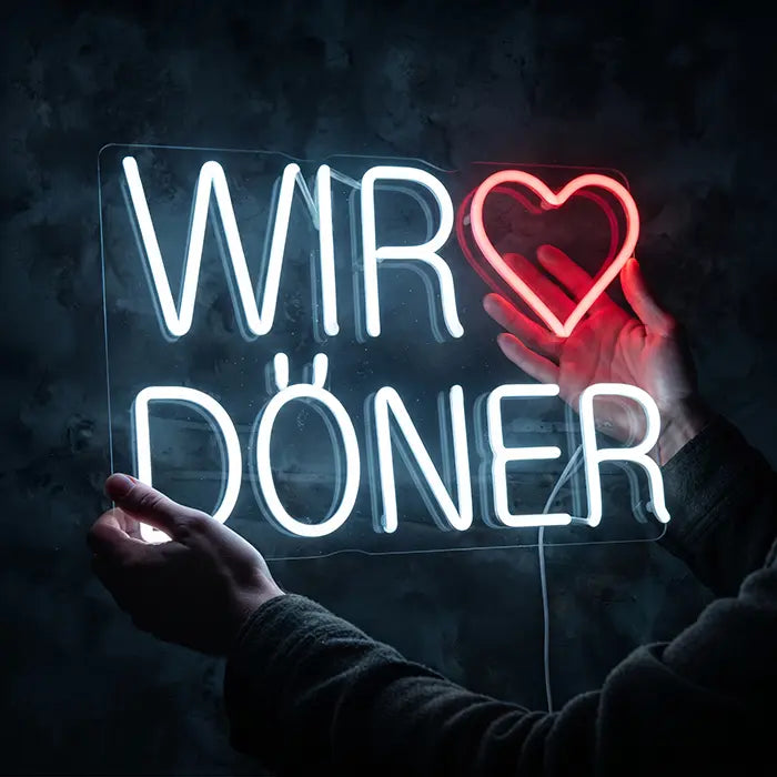 We Love Döner Neon LED Sign held by hand against a dark background, heart glowing red