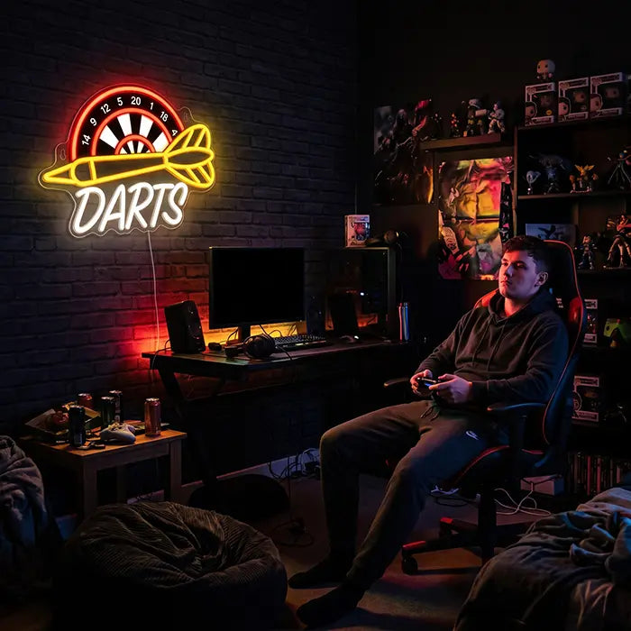 Darts Neon LED Sign with UV Print on a brick wall in a gaming room, a man with a controller in a gaming chair in front