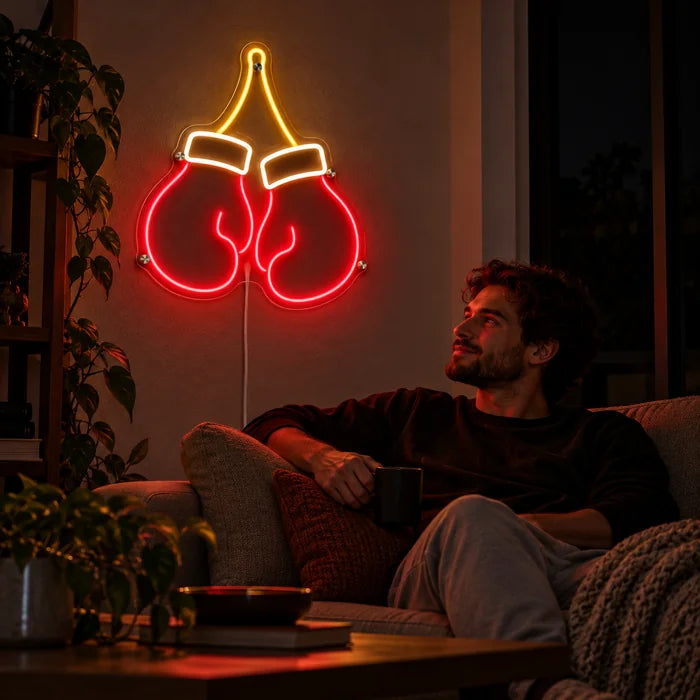 Boxing Gloves Neon LED Sign on a living room wall, a person relaxing on the sofa in front of it