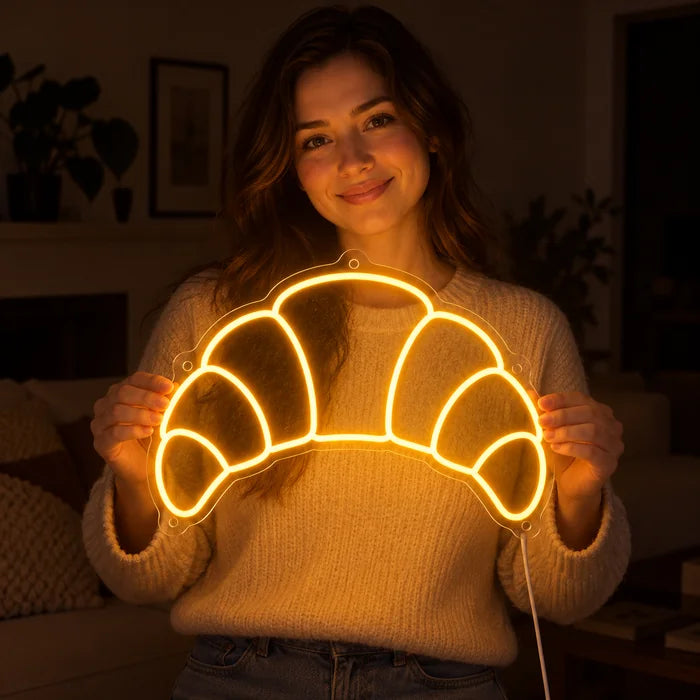 Butter Croissant Neon LED Sign held by a smiling woman against a dark background