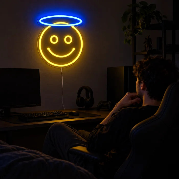 Angel Smiley Neon LED Sign above a gaming desk, a gamer in a gaming chair in front of it