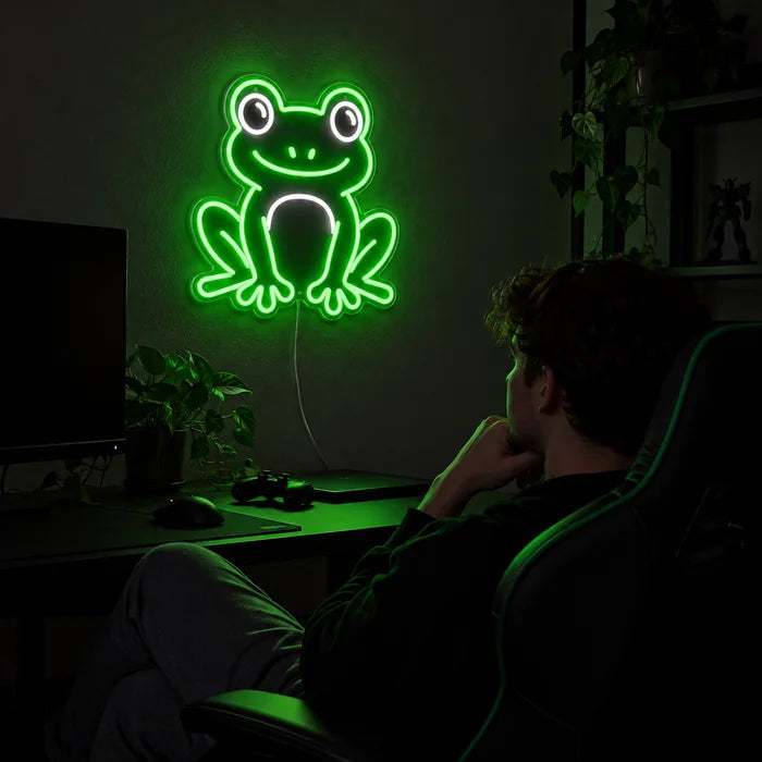 Frog Friend Neon LED Sign above a gaming desk, a gamer in a gaming chair in front of it