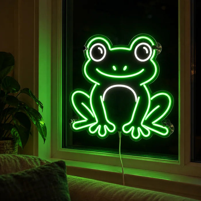 Frog Friend Neon LED Sign in the window of a cosy living room in the evening