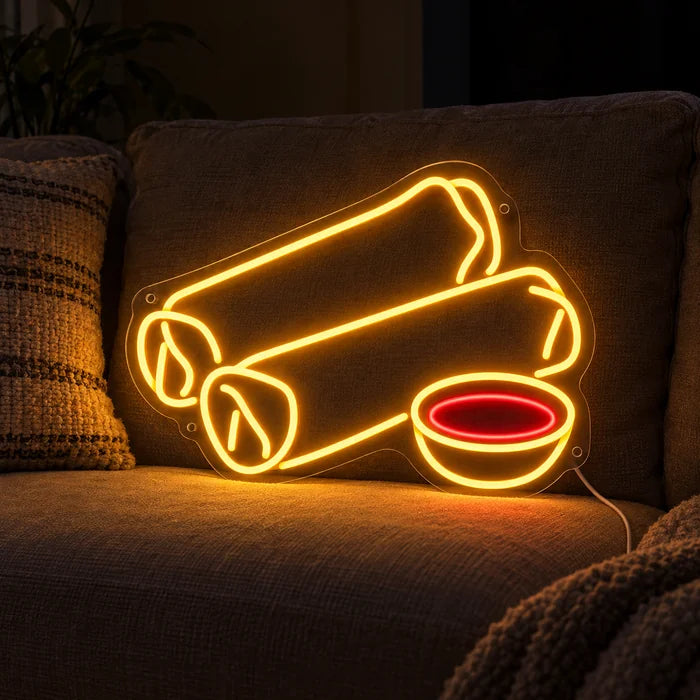 Spring Rolls Neon LED Sign on a cosy sofa between cushions and a throw