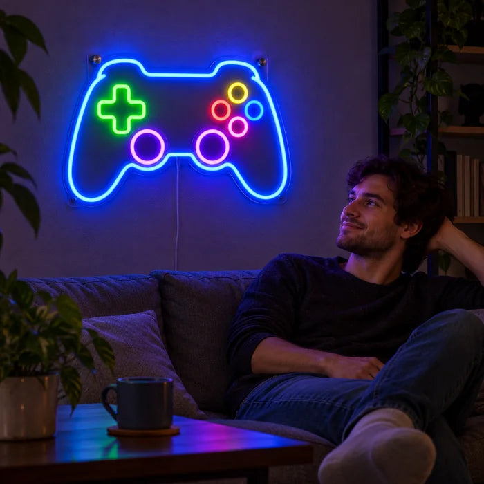 Insegna al neon LED Controller da gioco sulla parete del soggiorno, davanti una persona rilassata sul divano