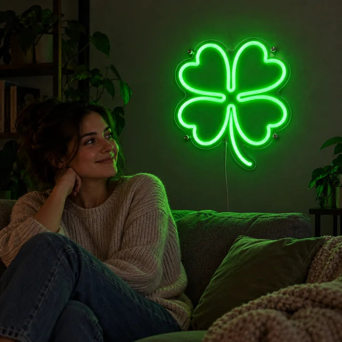 Neon LED-skilt Lykkekløver på stueveggen, foran slapper en person av på sofaen