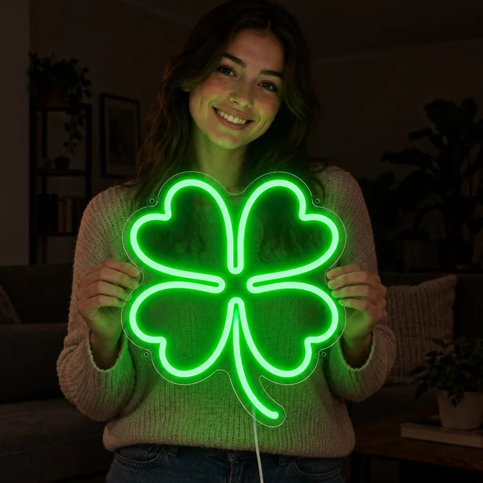 Neon LED-skilt Lykkekløver i hendene på en smilende kvinne mot mørk bakgrunn