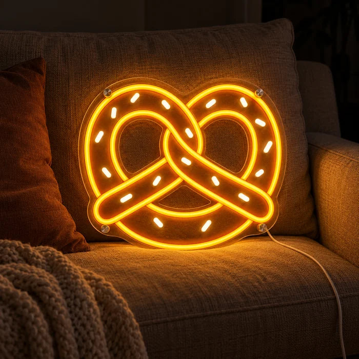 Golden Pretzel Neon LED Sign on a cosy sofa between cushions and a throw