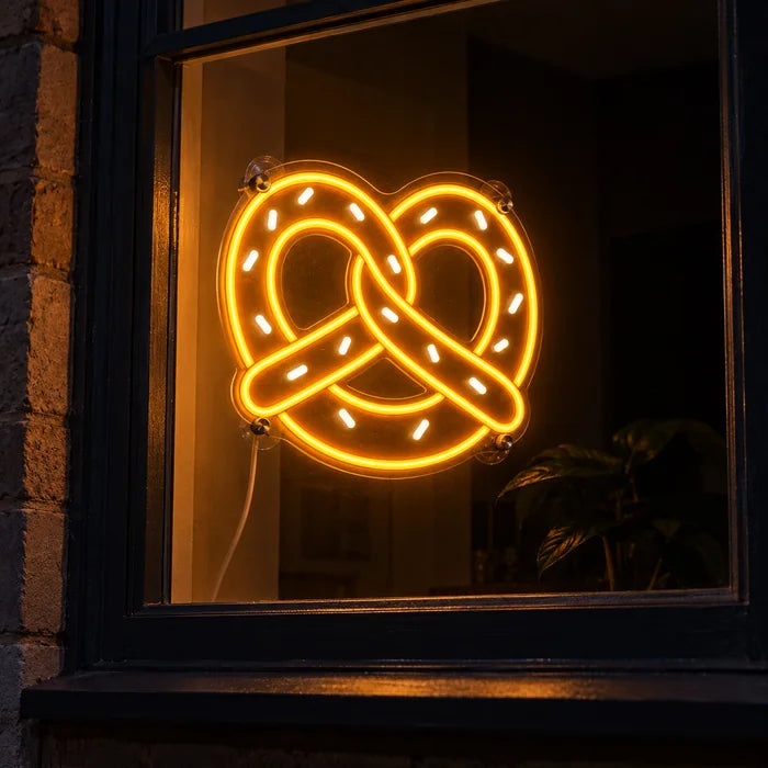 Golden Pretzel Neon LED Sign in a window, seen from the street at night