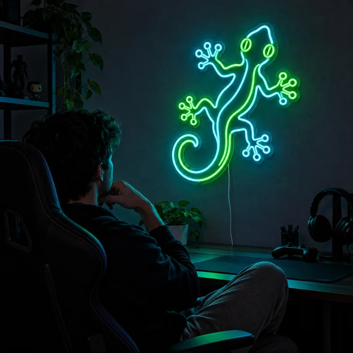 Green Gecko Neon LED Sign above a gaming desk, a gamer in a gaming chair in front of it