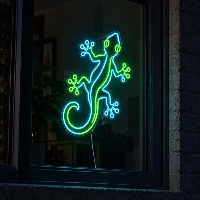 Green Gecko Neon LED Sign in a window, seen from the street at night