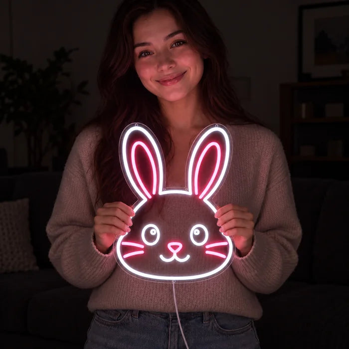 Pupun kasvot neon LED -kyltti hymyilevän naisen käsissä tummaa taustaa vasten