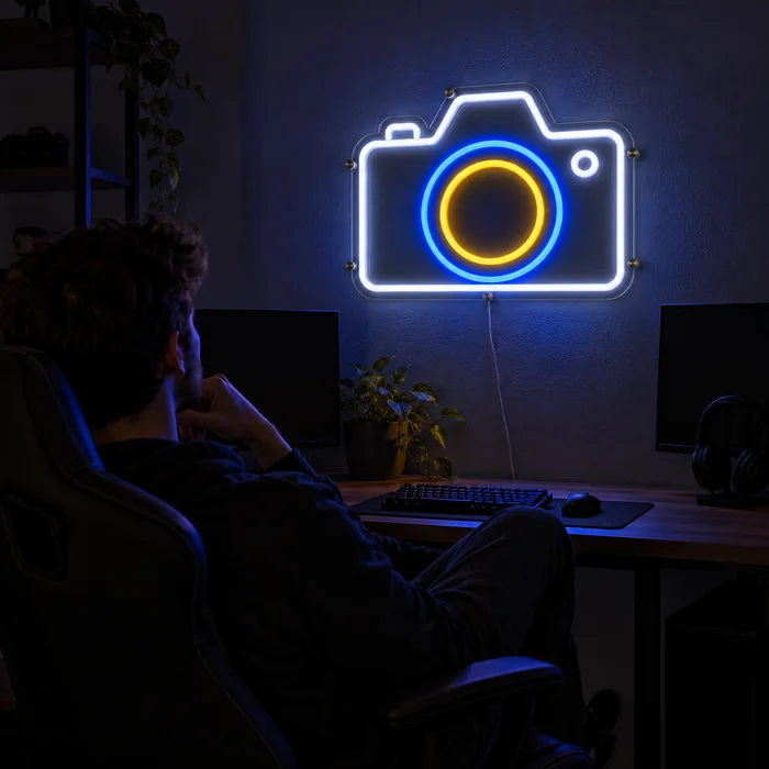 Camera Neon LED Sign above a gaming desk, a gamer in a gaming chair in front of it