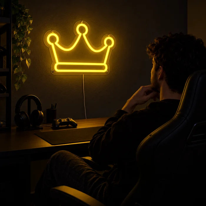 שלט ניאון LED כתר מלכותי מעל שולחן הגיימינג, לפניו שחקן בכיסא גיימינג