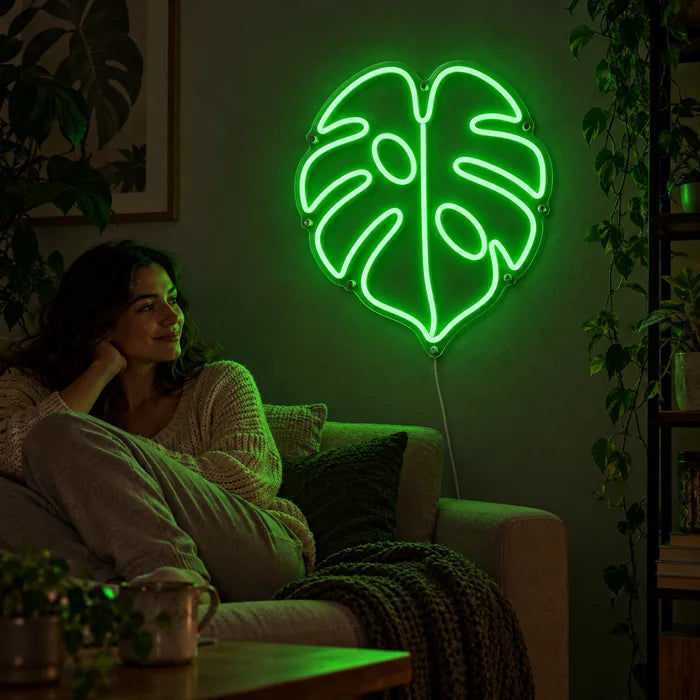 Monstera Leaf Neon LED Sign on a living room wall, a person relaxing on the sofa in front of it
