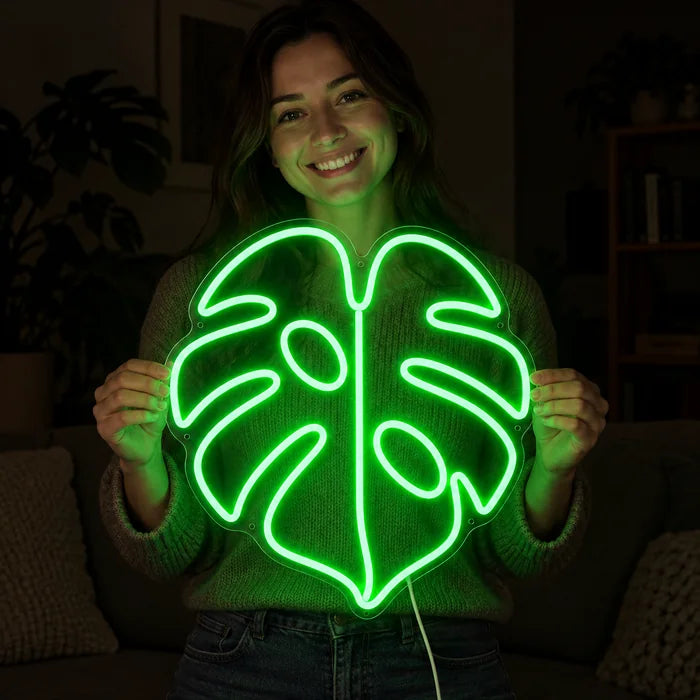 Monstera Leaf Neon LED Sign held by a smiling woman against a dark background