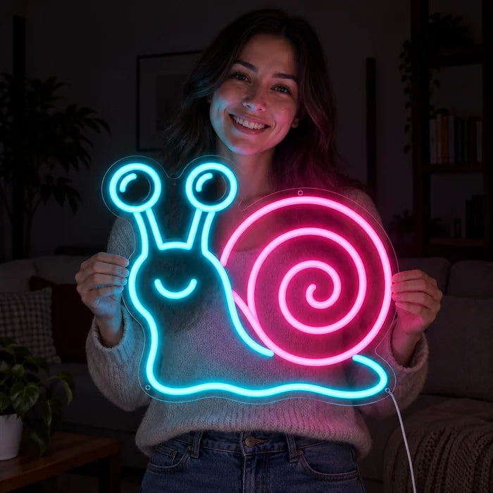 Neon Snail Neon LED Sign held by a smiling woman against a dark background
