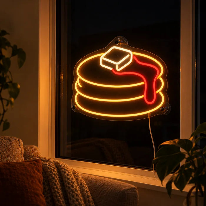 Pancakes Neon LED Sign in the window of a cosy living room in the evening