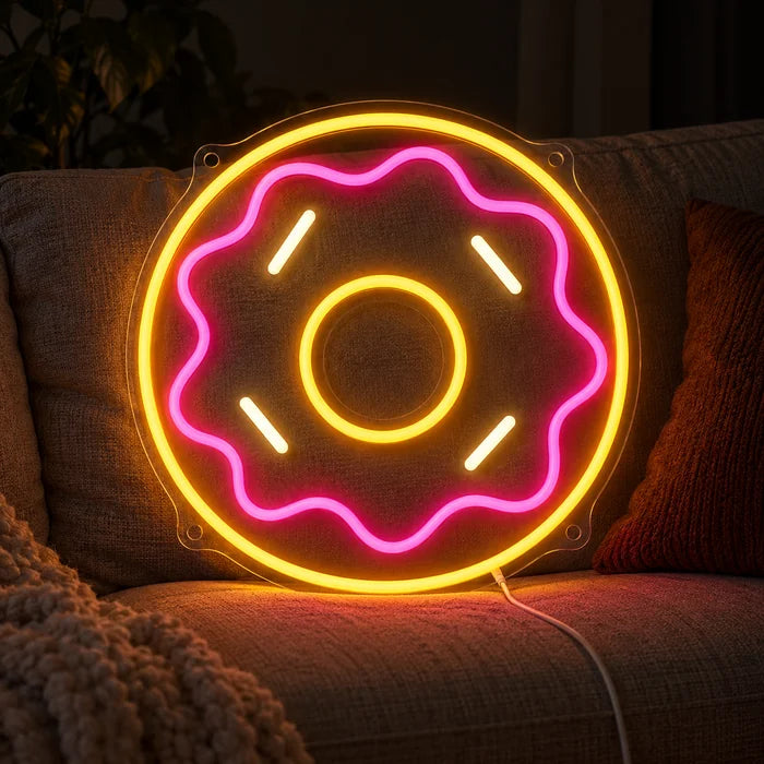 שלט ניאון LED דונאט ורוד על ספה נוחה בין כריות ושמיכה