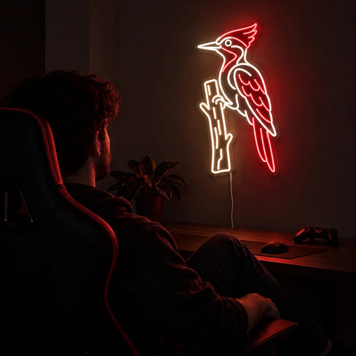 Red Woodpecker Neon LED Sign above a gaming desk, a gamer in a gaming chair in front of it