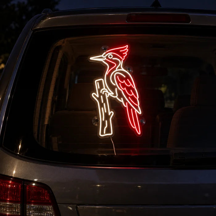 Red Woodpecker Neon LED Sign on the rear window of a car at night