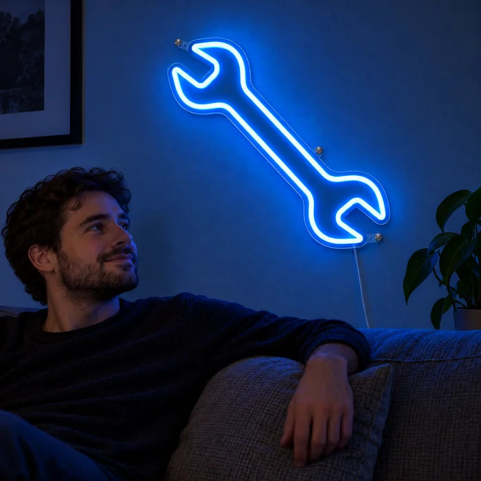 Neon LED bord Steeksleutel aan de woonkamerwand, ervoor ontspant een persoon op de bank
