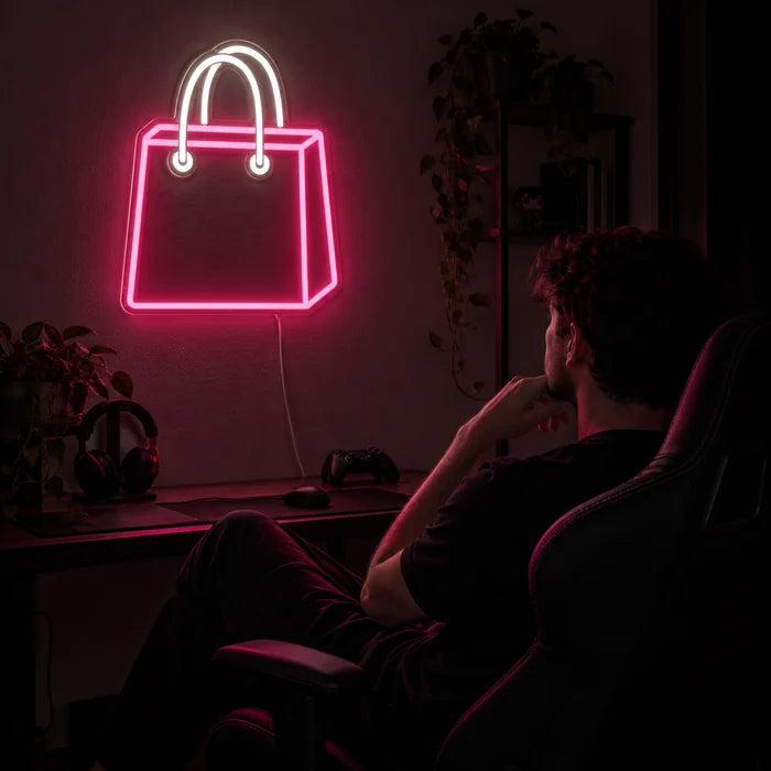 Shopping Bag Neon LED Sign above a gaming desk, a gamer in a gaming chair in front of it