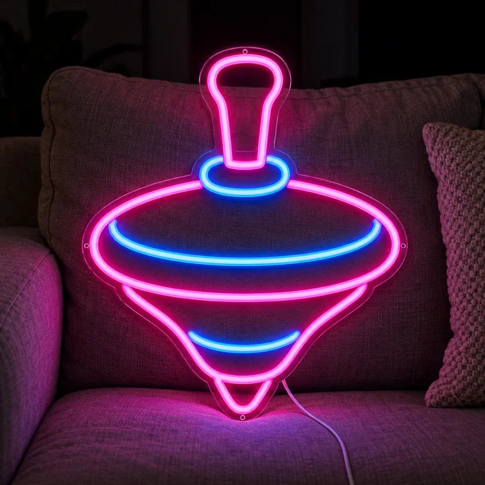Spinning Top Neon LED Sign on a cosy sofa between cushions and a throw